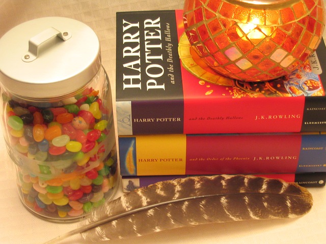 A candle laying on top of Harry potter books with a can of candy nex to the book