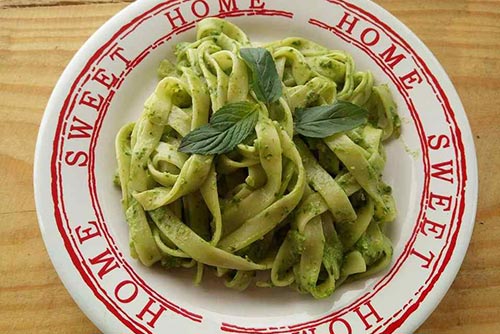A plate of avocado pasta garnished with herbs