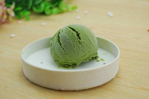A scoop of avocado ice cream on a white plate