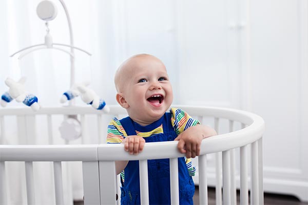 A little boy in a crib laughing joyously.