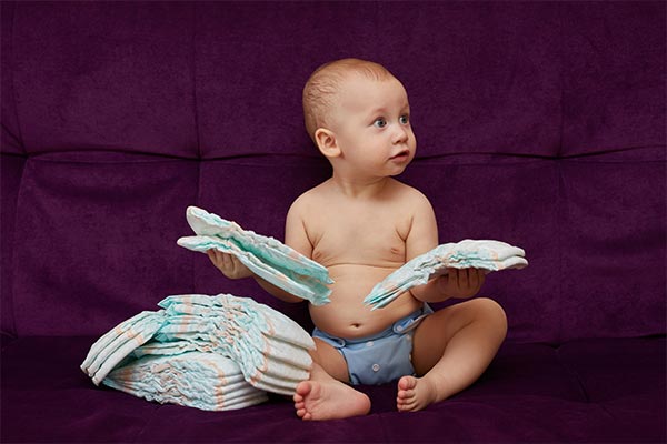 A boy sitting next to a pile of diapers.