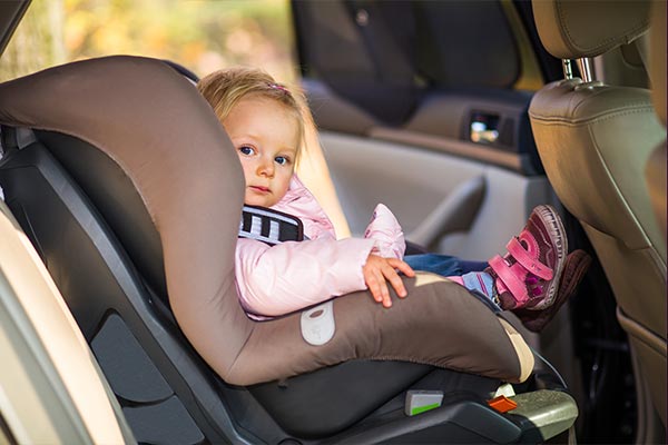 A young girl strapped to an infant car seat.