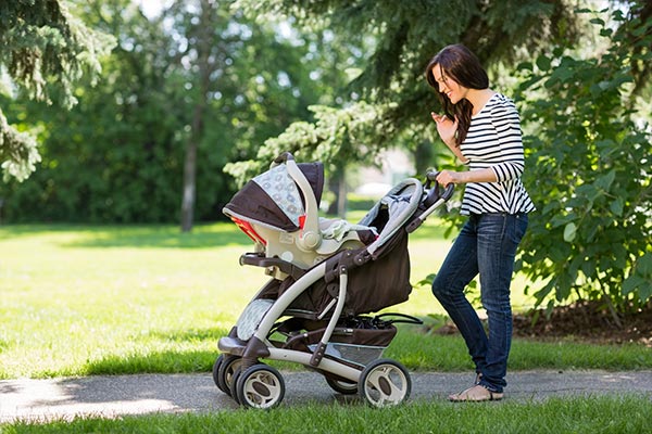 A mother waving to her child in a stroller.