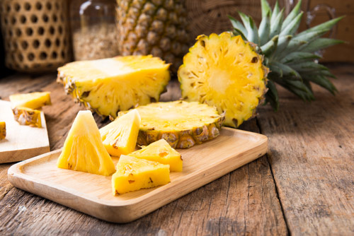 Chopped pineapples placed on a wooden tray.