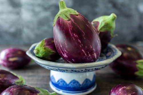 Ripe brinjals placed on a ceramic stand.