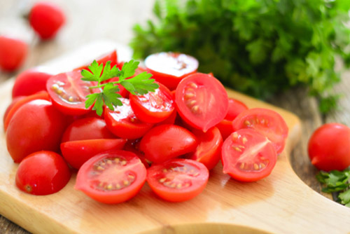 Chopped tomatoes placed on a wooden serving tray.