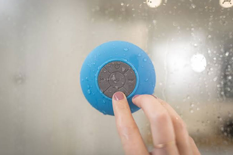 Picture of a hand operating a shower speaker in the shower