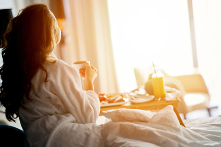 Rear image of a woman having breakfast in bed