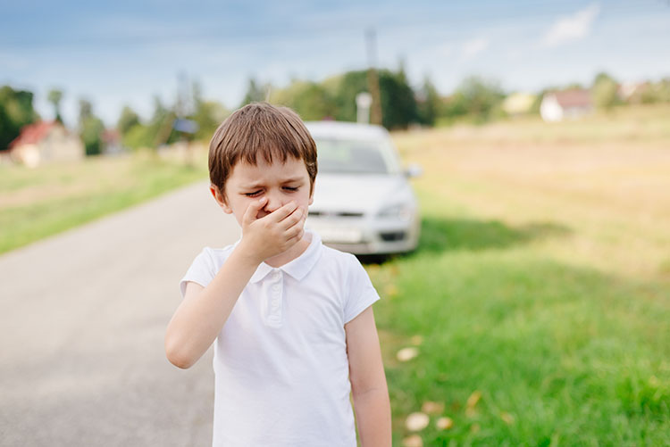 A boy feeling car sick after a long car drive.