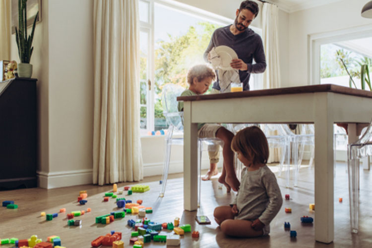 Man wiping dishes while the kids play