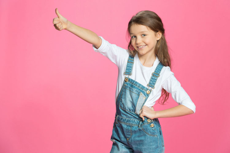 A girl in dungarees giving a thumbs up