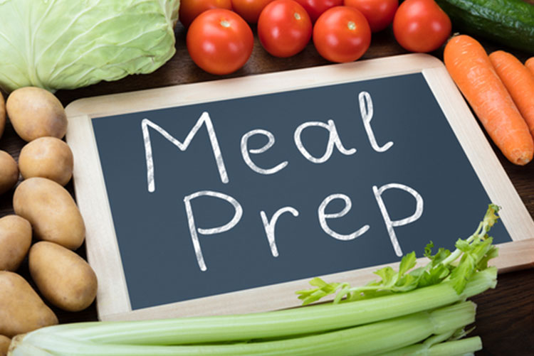 A board with 'Meal prep' written on it surrounded by vegetables